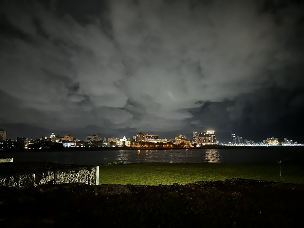 A nighttime photo with grey clouds and the lit skyline of Havana